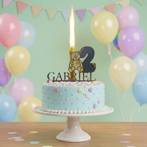 Personalised teddy bear cake topper with a child's name and age on a pastel first birthday cake